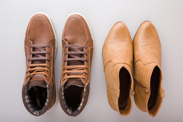 Male and female brown leather boots on gray floor background. Closeup. Footwear for daily walking...