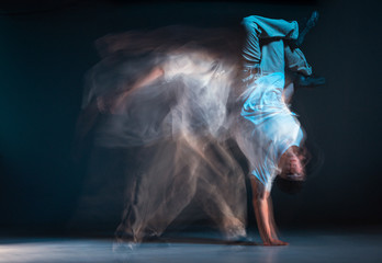 Young man breakdancer dancing hip-hop in neon light. Dance school poster. Long exposure shot