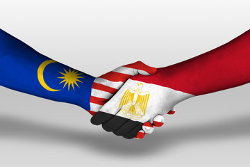 Handshake between egypt and malaysia flags painted on hands, illustration with clipping path.