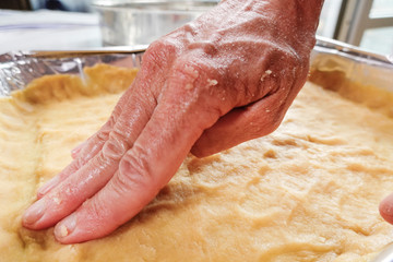 A woman makes pressed dough into a quiche form