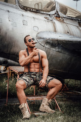 Crashed airplane and muscular military which smoking cigar