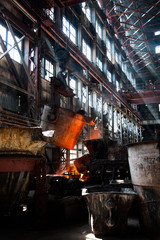 Metallurgy plant interior. Melting of metal. Metallurgy bucket with liquid hot metal. With orange light of electric arc furnace.