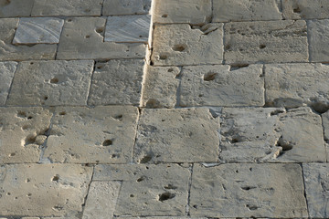 A white brick wall riddled with gunfire.