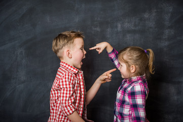 Boy and girl pointing fingers to each other. Raging kids - children shouting to each other against...
