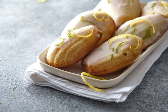 Madeleine cookies with lemon zest in a plate on a gray background.