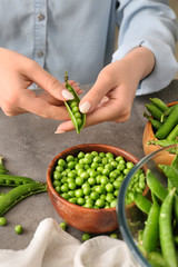 Woman preparing fresh peas on table