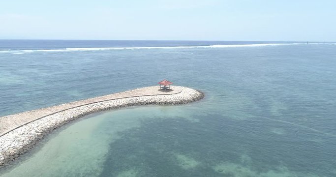 Drone orbit of man-made boulder bank to reveal beach in the background