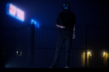A man in a creepy mask at night in a foggy city
