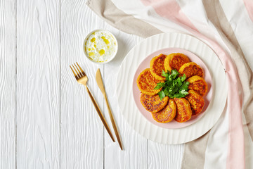 Curried pumpkin cakes on a white plate, copy space
