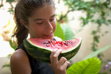  young girl eats a slice of watermelon
