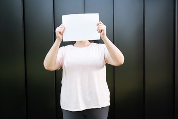 Fat woman holding blank paper over her face