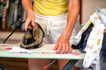 Ironing big heap of laundry on iron board