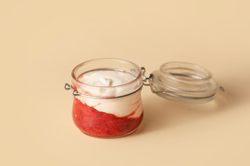 Jar of strawberry yogurt on color background