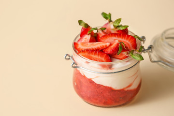 Jar of strawberry yogurt on color background