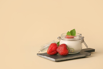 Jar of strawberry yogurt on color background