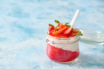 Jar of strawberry yogurt on color background