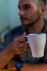 Joven con taza de cafe trabajando en el ordenador junto a la ventana