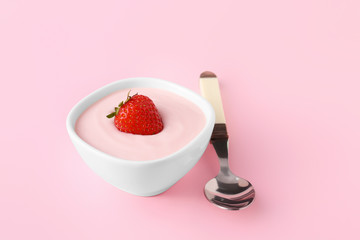 Bowl of strawberry yogurt on color background