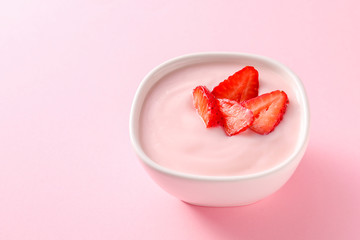 Bowl of strawberry yogurt on color background