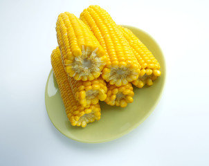 large cobs of ripe corn on a green plate, on a light background. Vitamins, vegetable diet, proper nutrition, healthy and balanced nutrition. A rich harvest from the garden. Wheat corn on a plate close