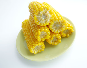 large cobs of ripe corn on a green plate, on a light background. Vitamins, vegetable diet, proper nutrition, healthy and balanced nutrition. A rich harvest from the garden. Wheat corn on a plate close