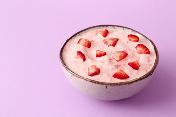 Bowl of strawberry yogurt on color background