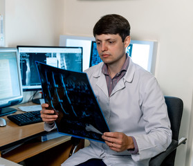 Doctor loking at x-ray image near computer. Magnetic resonance imaging machine diagnosing. Specialist at working place..