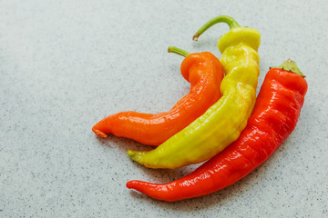 yellow, orange and red hot peppers on a gray table. Concept of the harvest season, bright autumn.