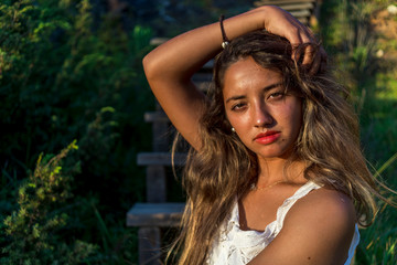 Naklejka premium Chica joven posando en unas escaleras de madera al tardecer en la playa