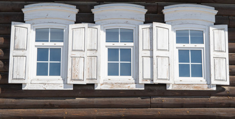 three old wooden Windows with open shutters. Old Russian country style.