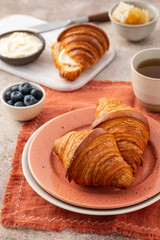 Fresh croissants with blueberries and honey, gray background.