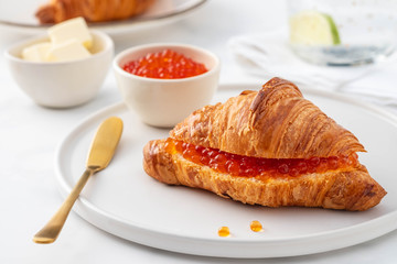 Red caviar and croissant for breakfast, selective focus. Luxury breakfast.