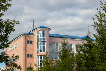 Pink old house with white Windows against the sky with clouds