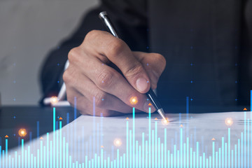 Businessman in suit signs contract. Double exposure with financial chart hologram. Man signing mortgage agreement. Real estate market analysis and investment concept.
