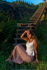 Obraz na płótnie Canvas Chica joven posando en unas escaleras de madera en la playa