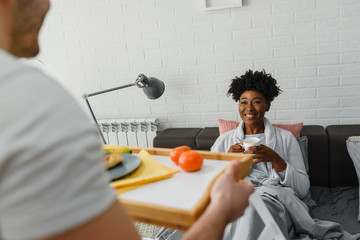 Young multiracial love couple having breakfast in bed
