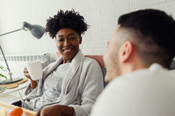 Young multiracial love couple having breakfast in bed