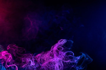 Conceptual image of multi-colored smoke isolated on dark black background, Halloween design element.