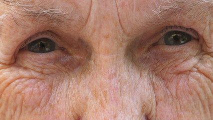 Close up of elderly grandma looks into camera with a sad sight. Portrait of senior grandmother...