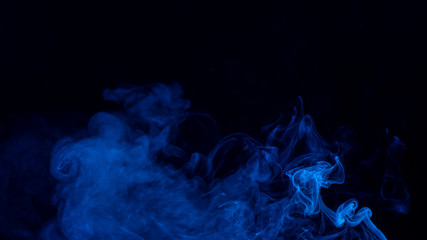 Conceptual image of blue color smoke isolated on dark black background, Halloween design element concept.