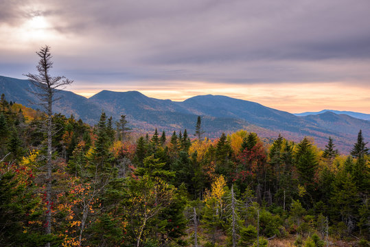 Dramatic sky over forested mountains at the peak of fall foliage colours at dusk. White Mountain National Forest, NH, USA.