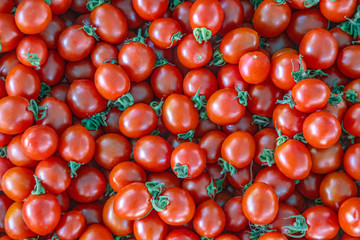 Raw market fresh cherry tomato background with multiple tomatoes lying on the market counter.