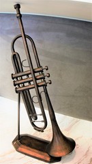 An old musical instrument called the trumpet. Brass- metal trumpet set on a wooden platform.
