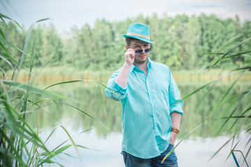 Young guy in turquoise shirt fashion outfit for men, clothes concept. Man rest at nature in fancy...