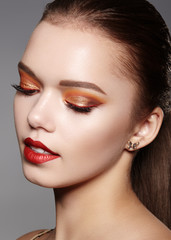 Fototapeta premium Closeup portrait of Woman Face with Gold glitter Make-up, bright red liner on Eyes. Fashion Celebrate Makeup, Glowy Skin