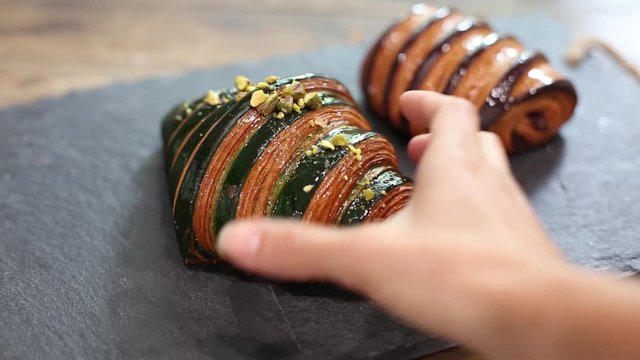 Hand reaching for and grabbing a delicious pistachio and chocolate glazed sweet croissants video