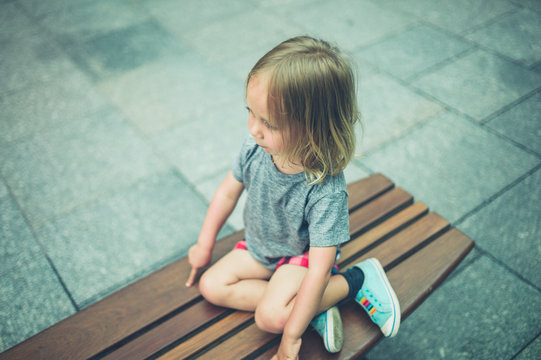 Preschooler sitting on a bench in the city