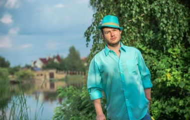 Young guy in turquoise shirt fashion outfit for men, clothes concept. Man rest at nature in fancy...