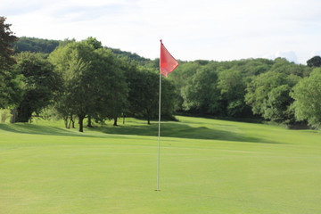 empty golf course with flag over the hole in summer