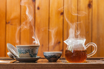 Chinese tea cup and glass kettle  with cloud of vapor on wooden background